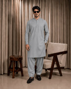 Man wearing light gray unstitched suiting fabric for formal wear with black loafers and sunglasses